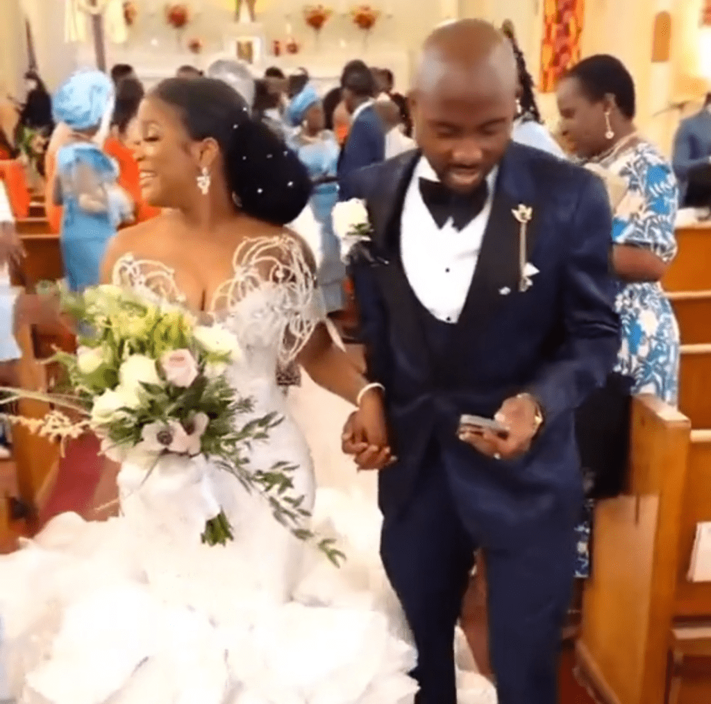 Groom pressing phone while walking down the Aisle with bride